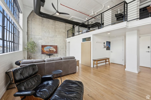 living room featuring a towering ceiling, ceiling fan, and wood finished floors