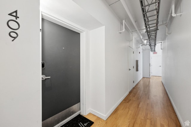 hall with light wood-style floors and baseboards