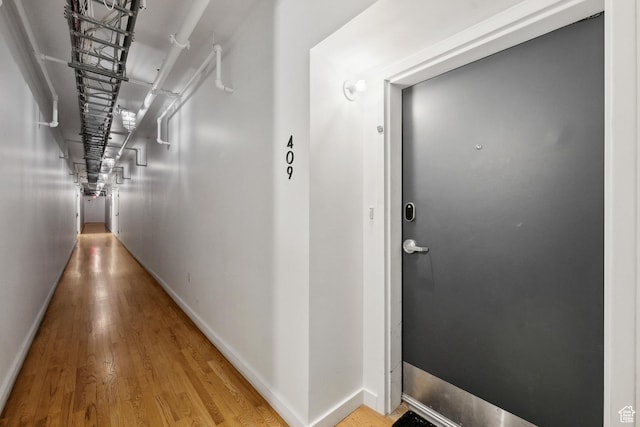 hallway featuring wood finished floors and baseboards