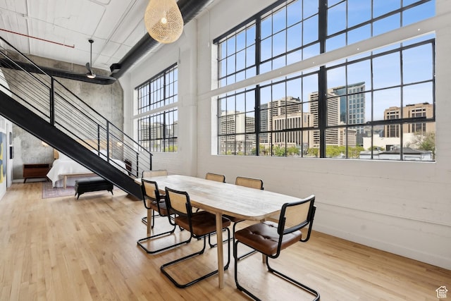 dining area featuring a towering ceiling, wood finished floors, stairs, a view of city, and baseboards