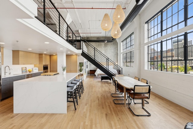 common area with a towering ceiling, stairs, a sink, and recessed lighting