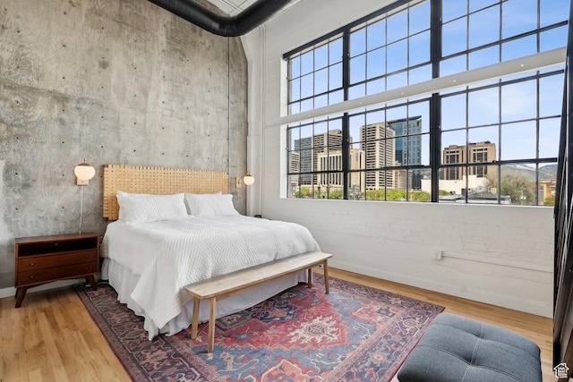 bedroom with wood finished floors, a high ceiling, and baseboards