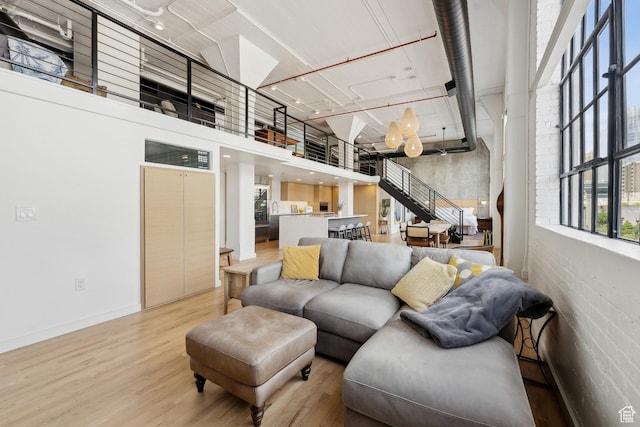 living room featuring light wood finished floors, baseboards, and a towering ceiling