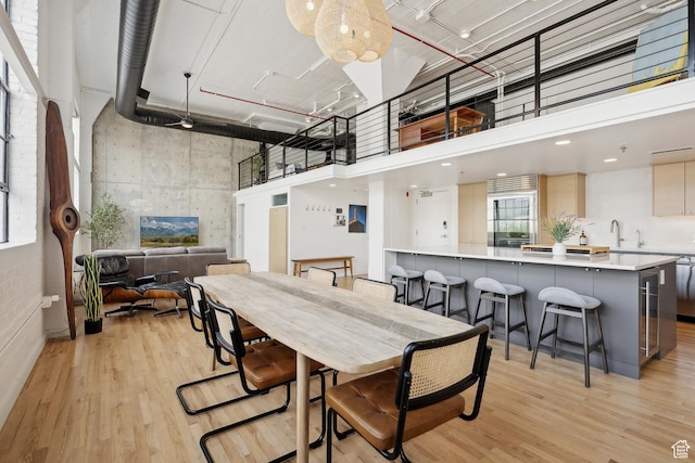 dining space featuring a towering ceiling and light wood-style floors