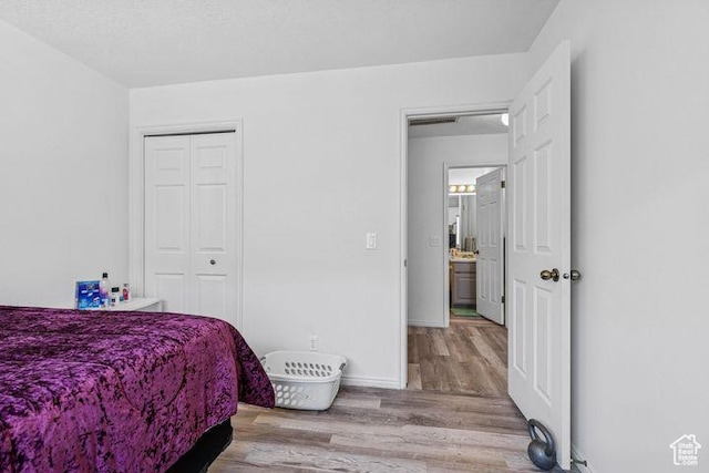bedroom featuring wood finished floors, a closet, and baseboards