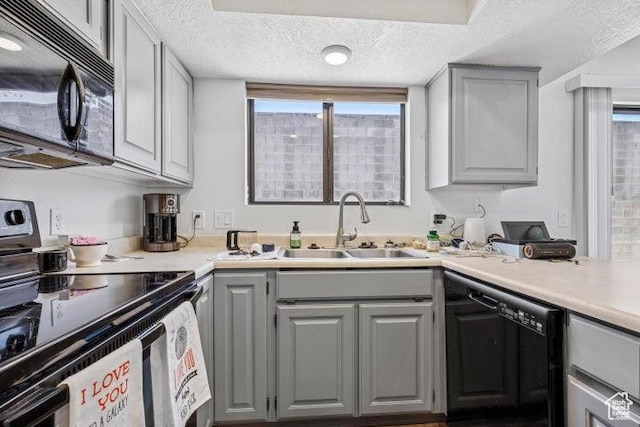 kitchen featuring black appliances, gray cabinetry, a sink, a textured ceiling, and healthy amount of natural light