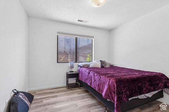 bedroom featuring a textured ceiling, wood finished floors, and baseboards