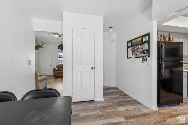 corridor featuring light wood-style flooring and baseboards