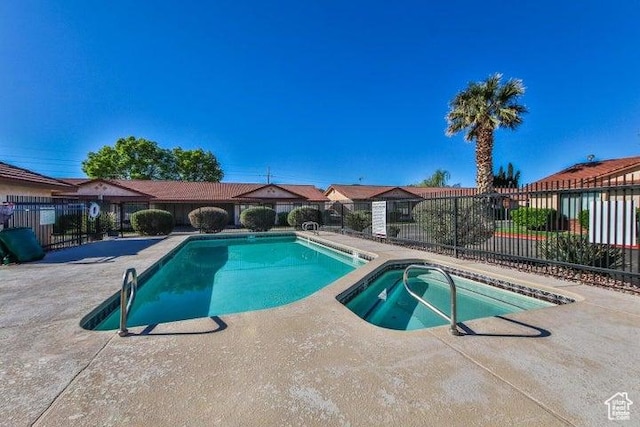 view of pool with fence, a patio area, and a pool with connected hot tub