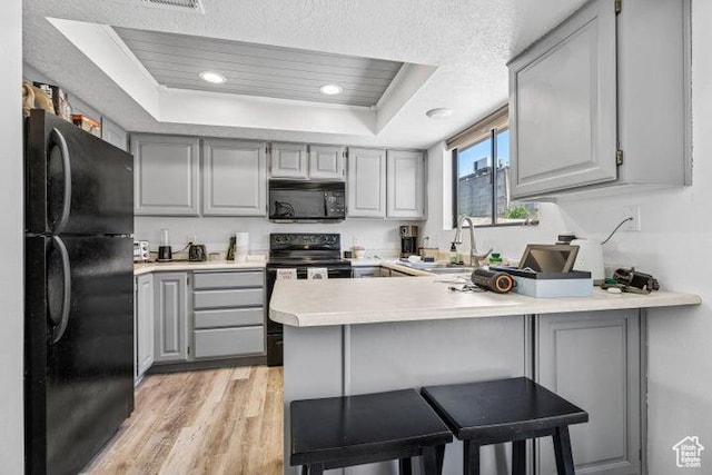 kitchen with black appliances, gray cabinetry, a raised ceiling, a peninsula, and recessed lighting