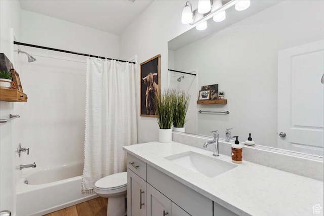 bathroom featuring wood finished floors, toilet, vanity, and shower / bath combo