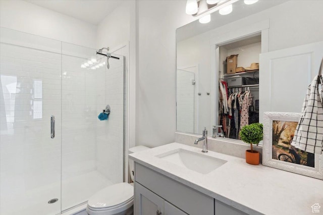 full bathroom with a shower stall, toilet, vanity, and a spacious closet
