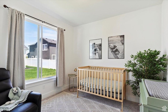 carpeted bedroom featuring multiple windows, baseboards, and a nursery area
