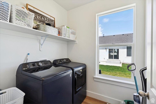 laundry room with washing machine and dryer, baseboards, and wood finished floors