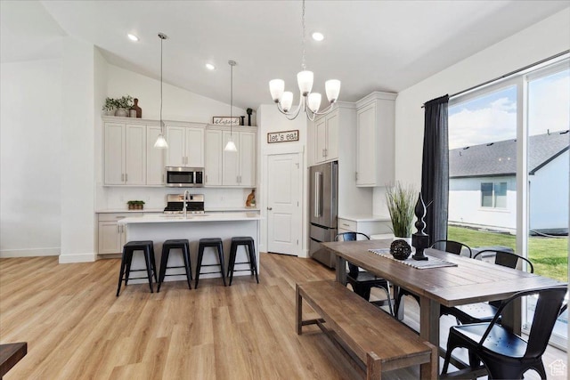 dining space with a chandelier, light wood finished floors, lofted ceiling, baseboards, and recessed lighting