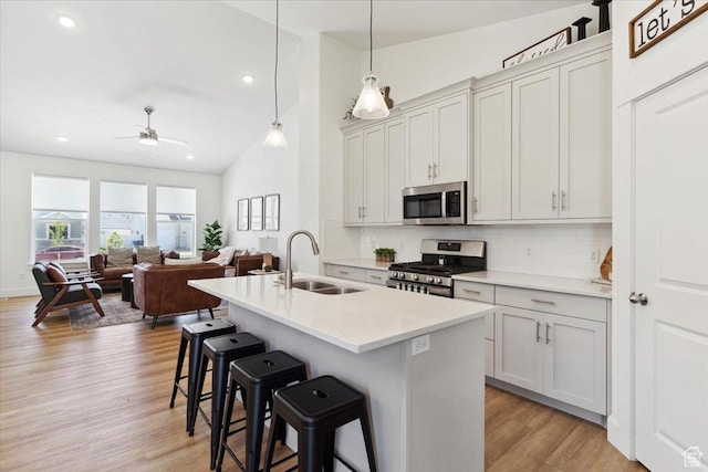kitchen featuring stainless steel appliances, a sink, tasteful backsplash, lofted ceiling, and a kitchen breakfast bar
