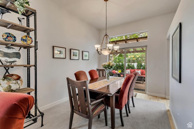 dining room featuring baseboards, light wood-style flooring, a chandelier, and a towering ceiling