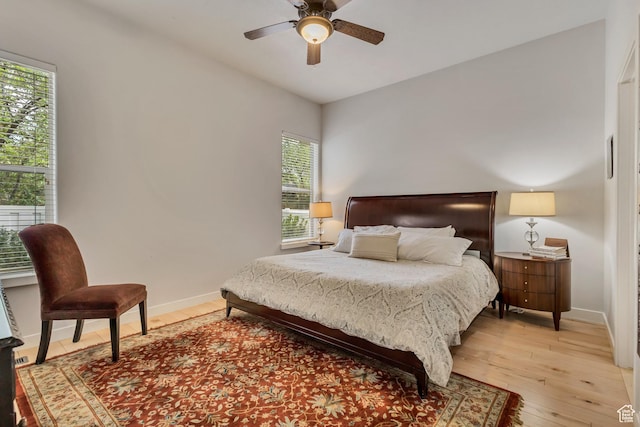 bedroom with light wood-style flooring, baseboards, and a ceiling fan