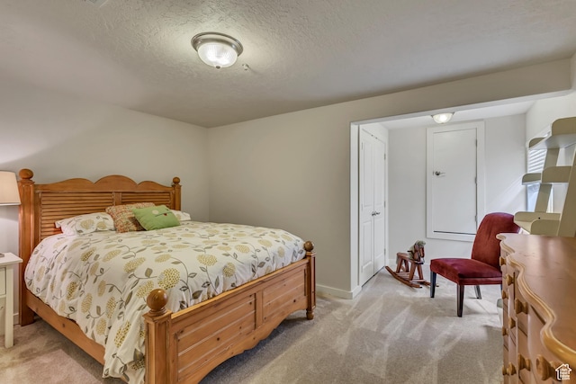 bedroom with light carpet, a textured ceiling, and baseboards