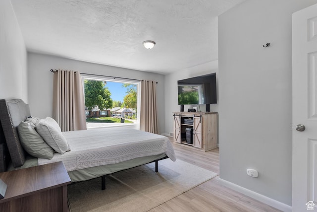 bedroom with light wood-type flooring, baseboards, and a textured ceiling
