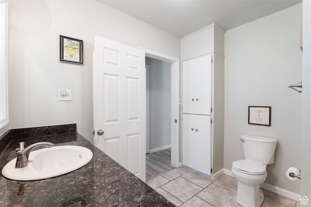 bathroom with a sink, toilet, tile patterned floors, and baseboards