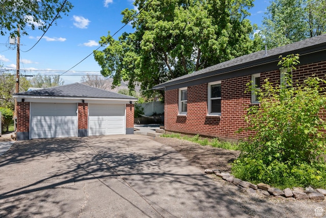 view of side of home with brick siding, an outdoor structure, and a garage