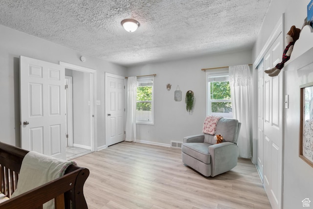 bedroom with light wood-style flooring, multiple windows, baseboards, and a textured ceiling