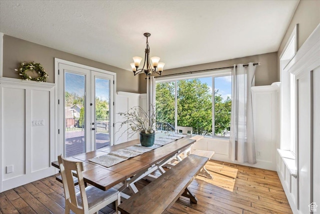 916 Country Ln, Farmington, UT 84025 - dining area featuring light wood finished floors, a chandelier, french doors, and a decorative wall