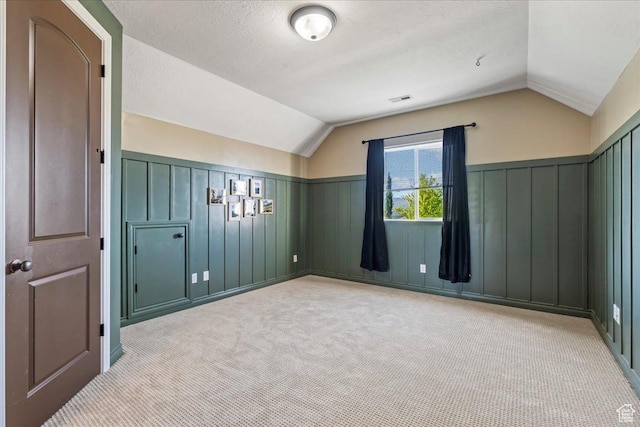 916 Country Ln, Farmington, UT 84025 - bonus room with vaulted ceiling, light carpet, wainscoting, a decorative wall, and a textured ceiling