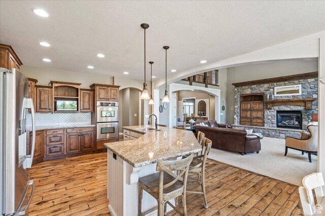 916 Country Ln, Farmington, UT 84025 - kitchen with appliances with stainless steel finishes, arched walkways, a sink, light wood-style flooring, and open floor plan