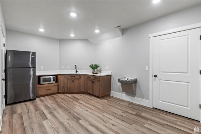 916 Country Ln, Farmington, UT 84025 - kitchen with freestanding refrigerator, stainless steel microwave, a sink, light wood finished floors, and light countertops