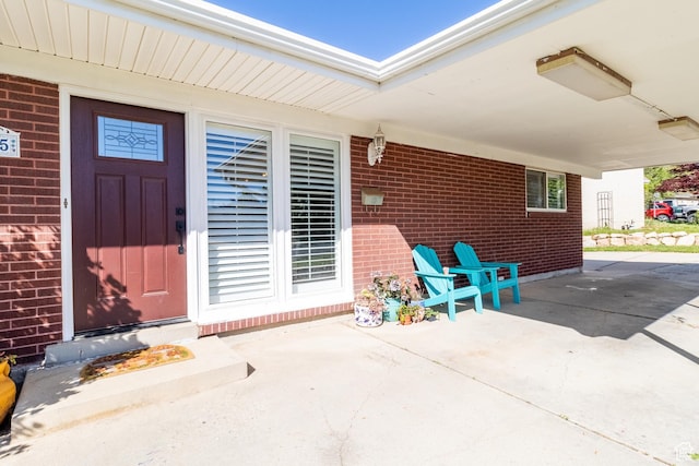property entrance with brick siding and a patio area