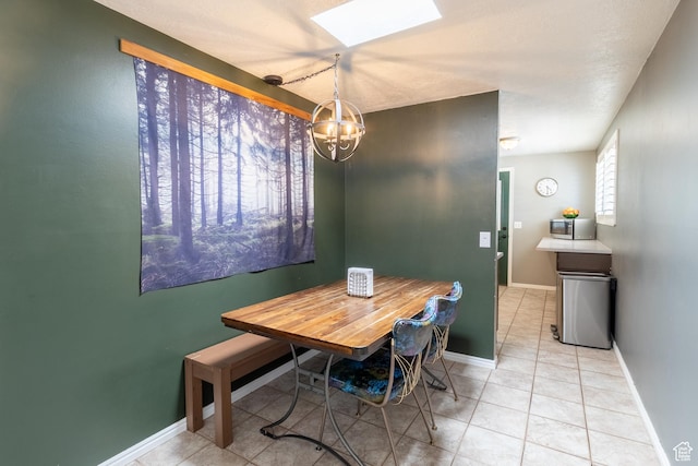 dining area featuring a chandelier, a skylight, light tile patterned flooring, and baseboards