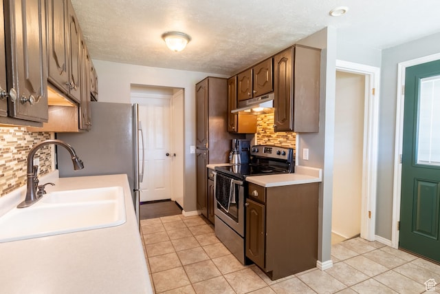kitchen featuring stainless steel range with electric stovetop, under cabinet range hood, a sink, light countertops, and backsplash