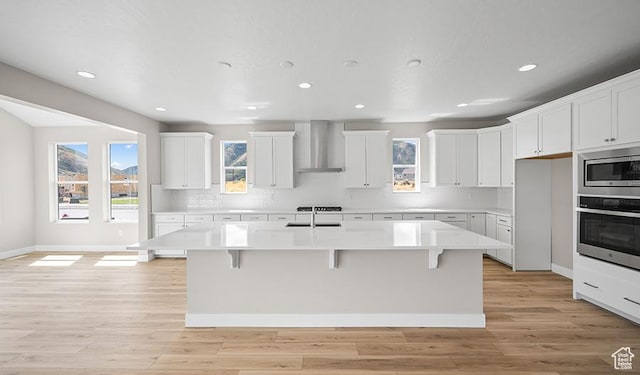 1147 S 3170 E Unit 207, Spanish Fork, UT 84660 - kitchen featuring wall chimney range hood, appliances with stainless steel finishes, recessed lighting, light countertops, and a kitchen bar