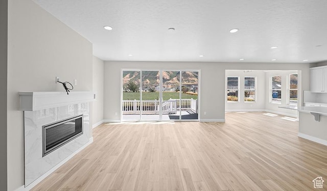 1147 S 3170 E Unit 207, Spanish Fork, UT 84660 - unfurnished living room with baseboards, a fireplace, light wood-style floors, and recessed lighting