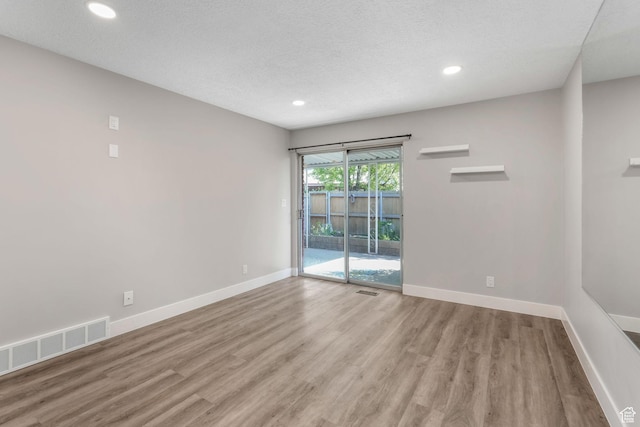 spare room with wood finished floors, baseboards, recessed lighting, and a textured ceiling