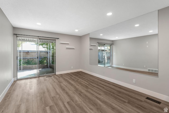 unfurnished room with wood finished floors, recessed lighting, baseboards, and plenty of natural light