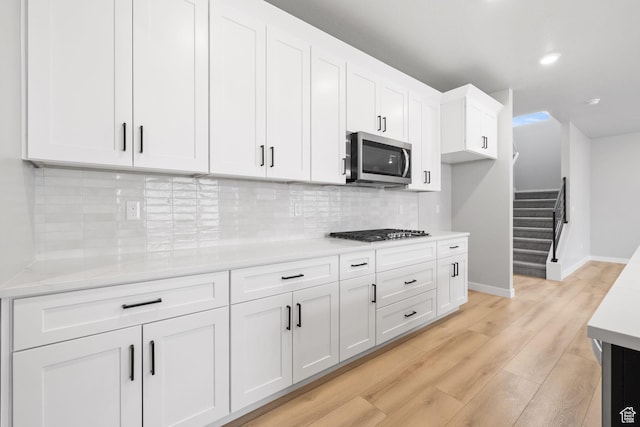 kitchen with appliances with stainless steel finishes, light wood-type flooring, white cabinetry, light countertops, and recessed lighting