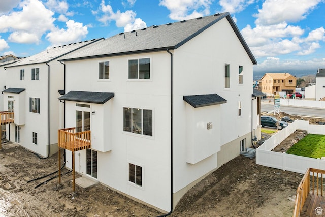 back of property featuring stucco siding, fence, and a residential view