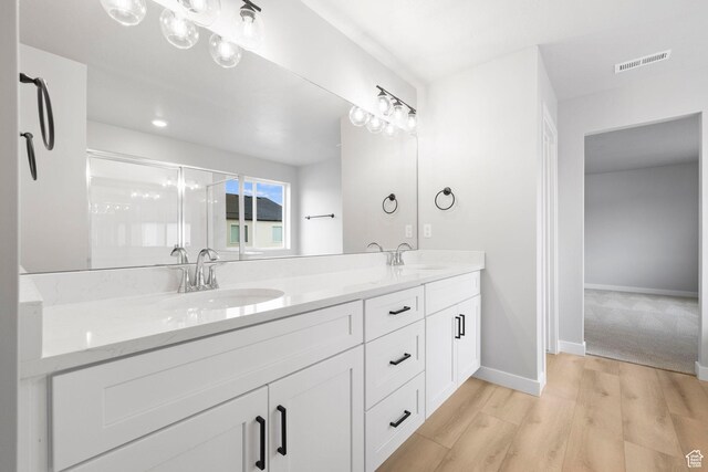 bathroom featuring double vanity, wood finished floors, and baseboards