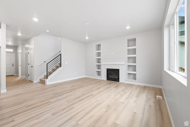 unfurnished living room with baseboards, stairway, light wood-type flooring, and recessed lighting