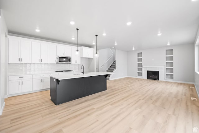 kitchen with stainless steel microwave, a sink, white cabinetry, baseboards, and recessed lighting
