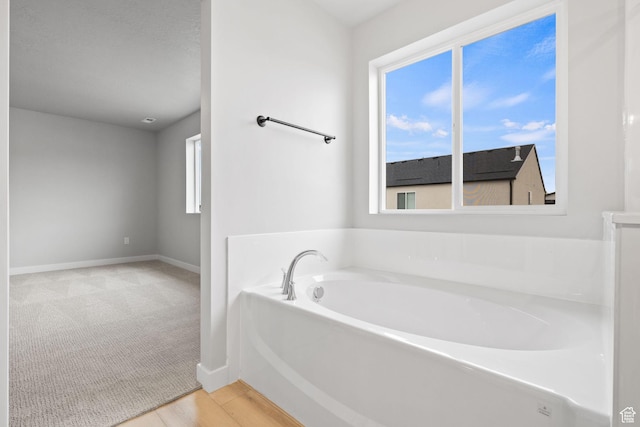full bathroom with a garden tub and baseboards