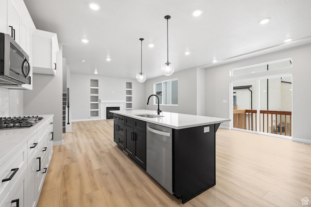 kitchen featuring appliances with stainless steel finishes, a sink, dark cabinetry, light countertops, and recessed lighting