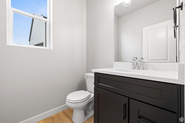 bathroom with wood finished floors, vanity, baseboards, and toilet