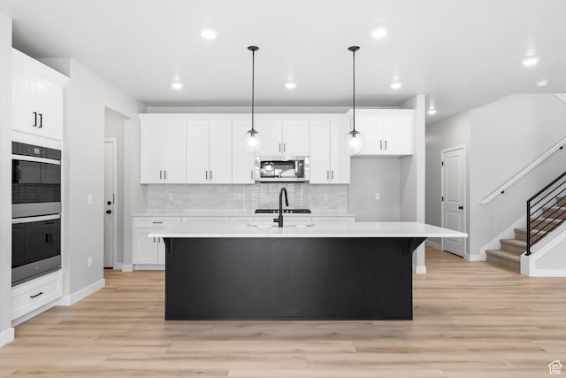 kitchen with stainless steel microwave, multiple ovens, backsplash, light countertops, and recessed lighting