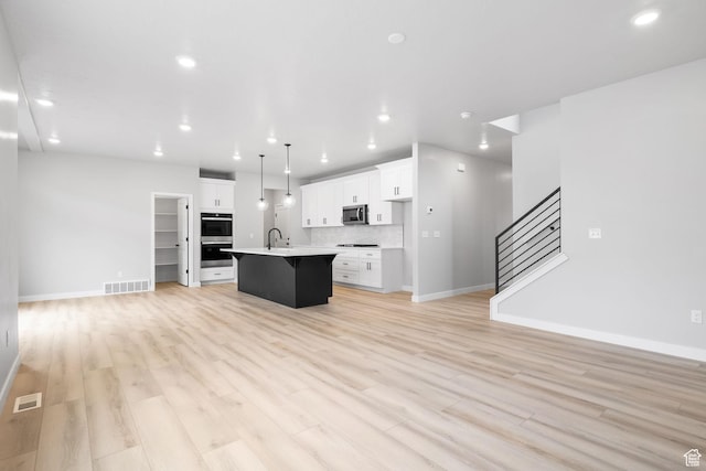 kitchen with stainless steel appliances, open floor plan, a kitchen island with sink, recessed lighting, and a breakfast bar area