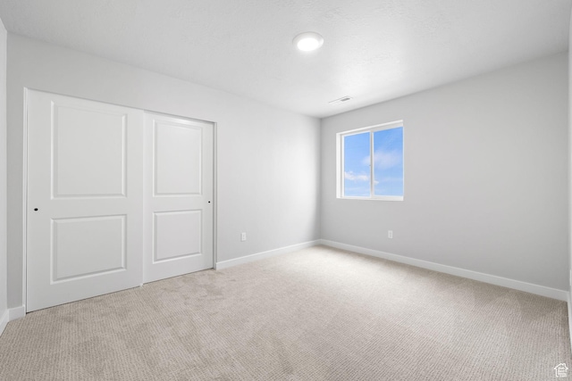 unfurnished bedroom featuring carpet flooring, baseboards, and a closet