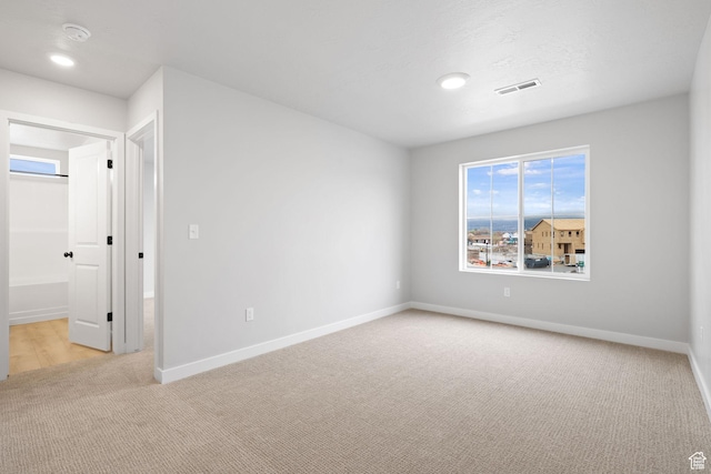 spare room with light colored carpet, baseboards, a smoke detector, and recessed lighting